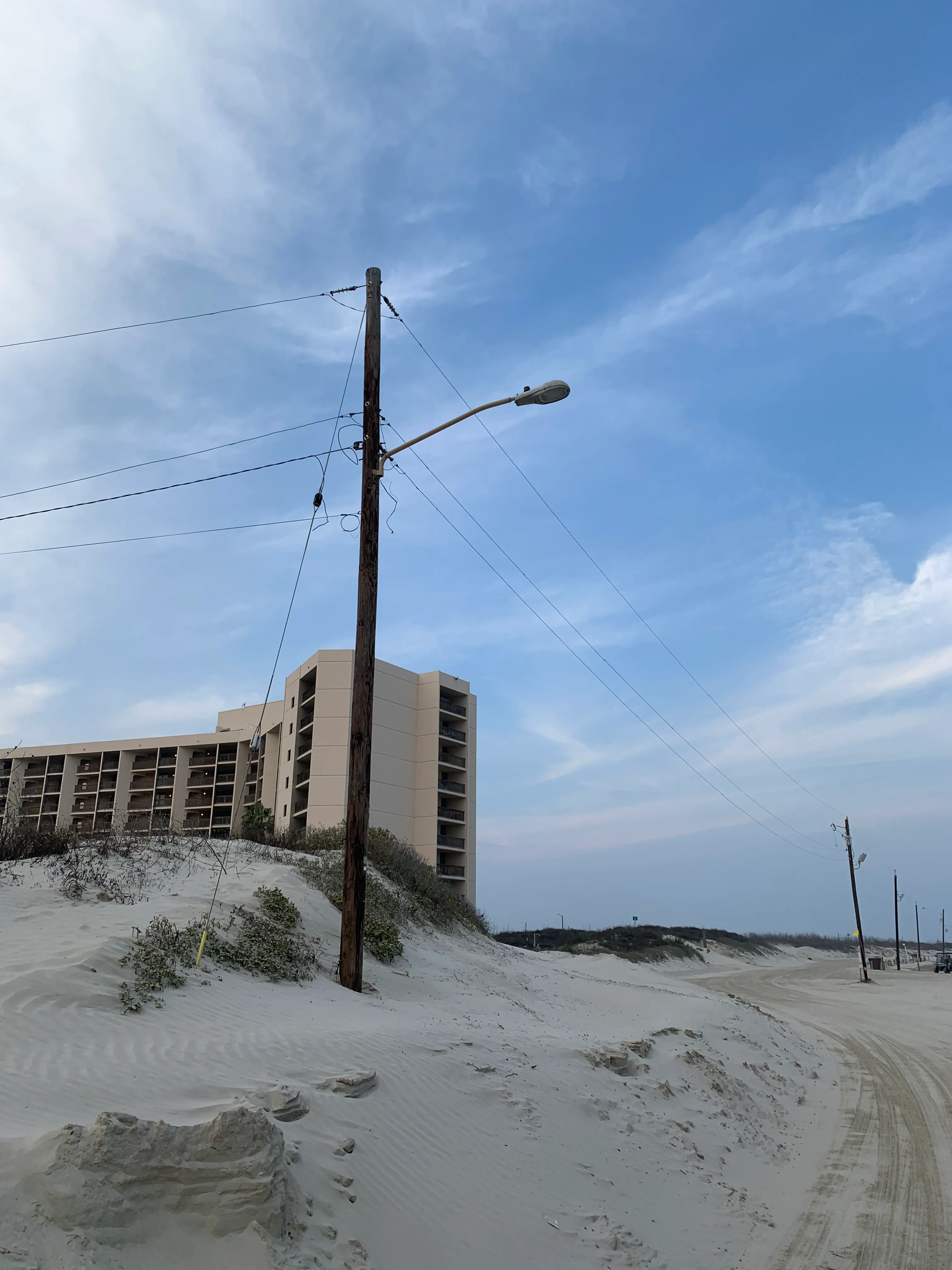 A utility pole with a streetlight beside beach dunes in Port Aransas, Texas.